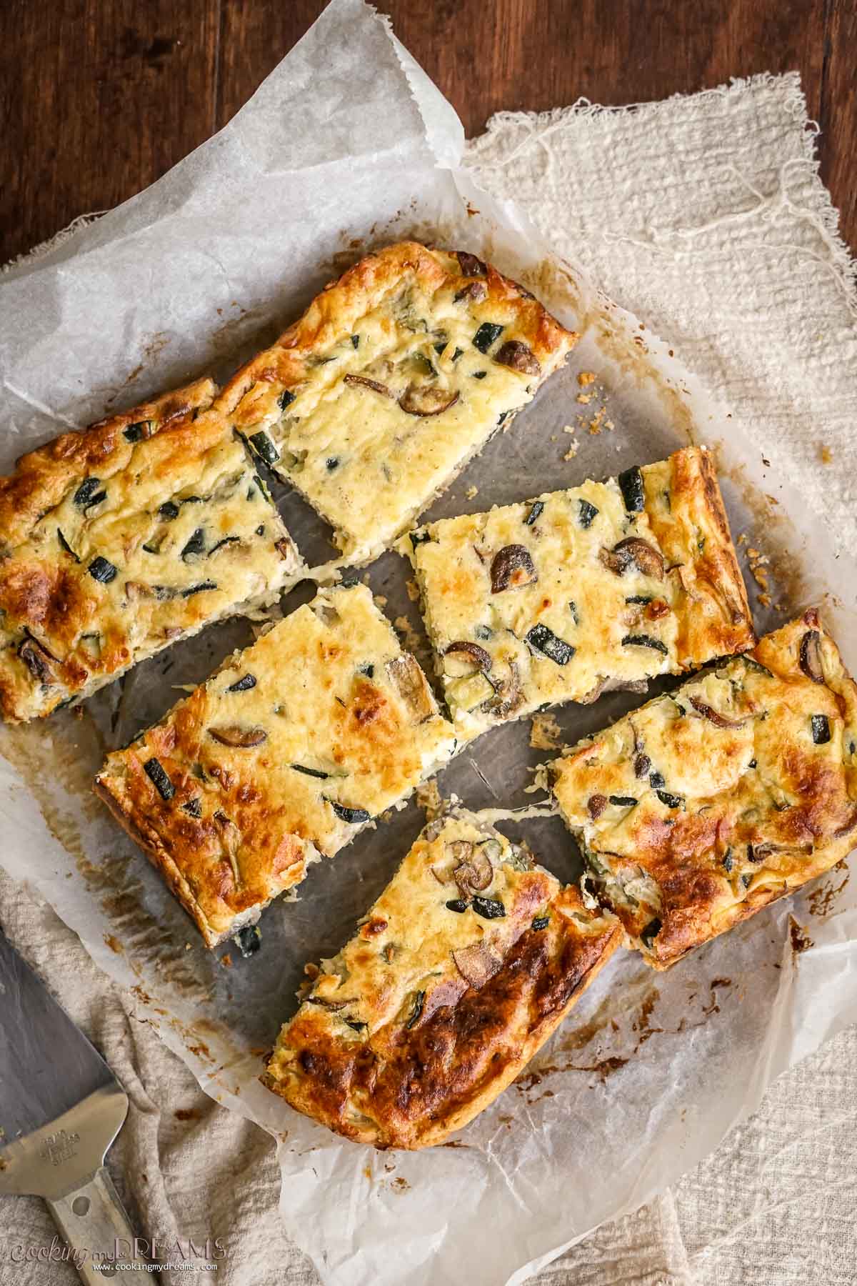 6 pieces of zucchini mushroom quiche on a cutting board.