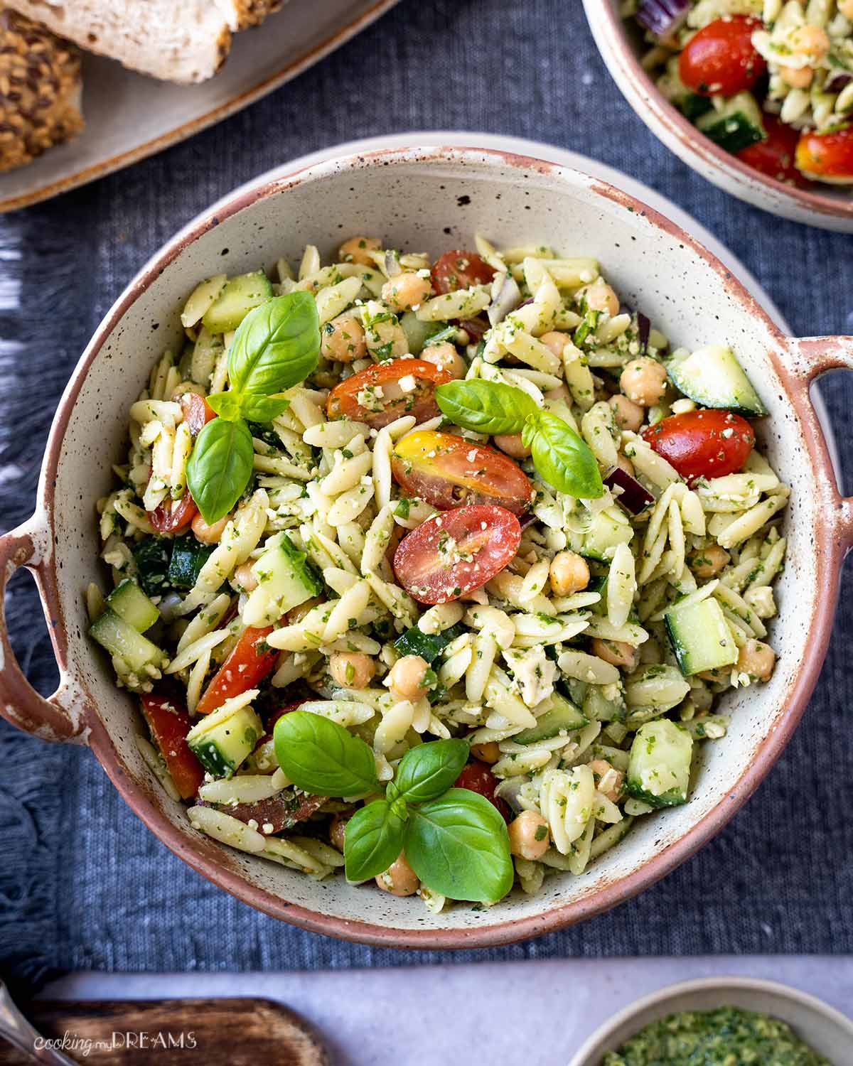 bowl of pasta salad with tomatoes and basil leaves on top