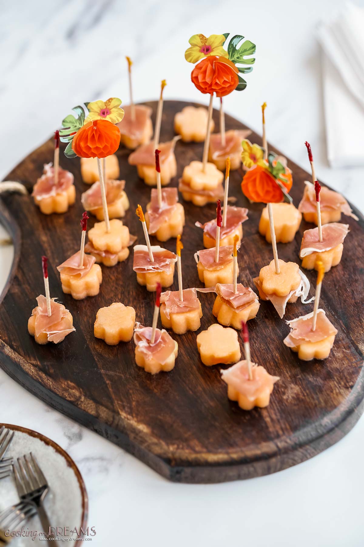 prosciutto and melon bites on a wooden board.