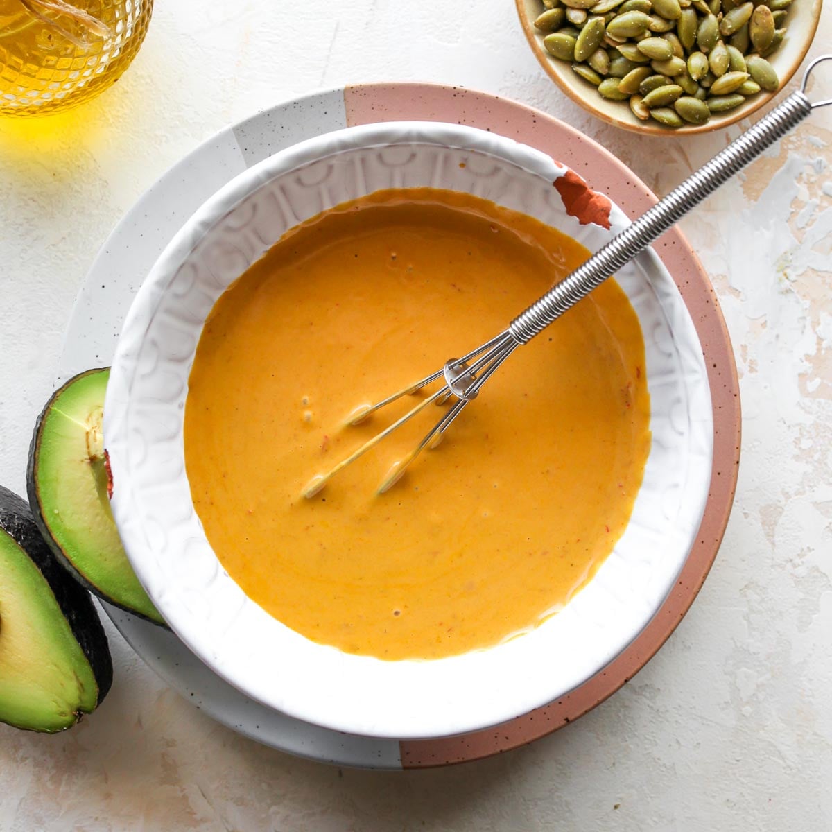 Golden tahini dressing being whisked in a white bowl